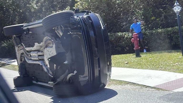 Tiger Woods standing beside overturned vehicle after crash in Jupiter Island