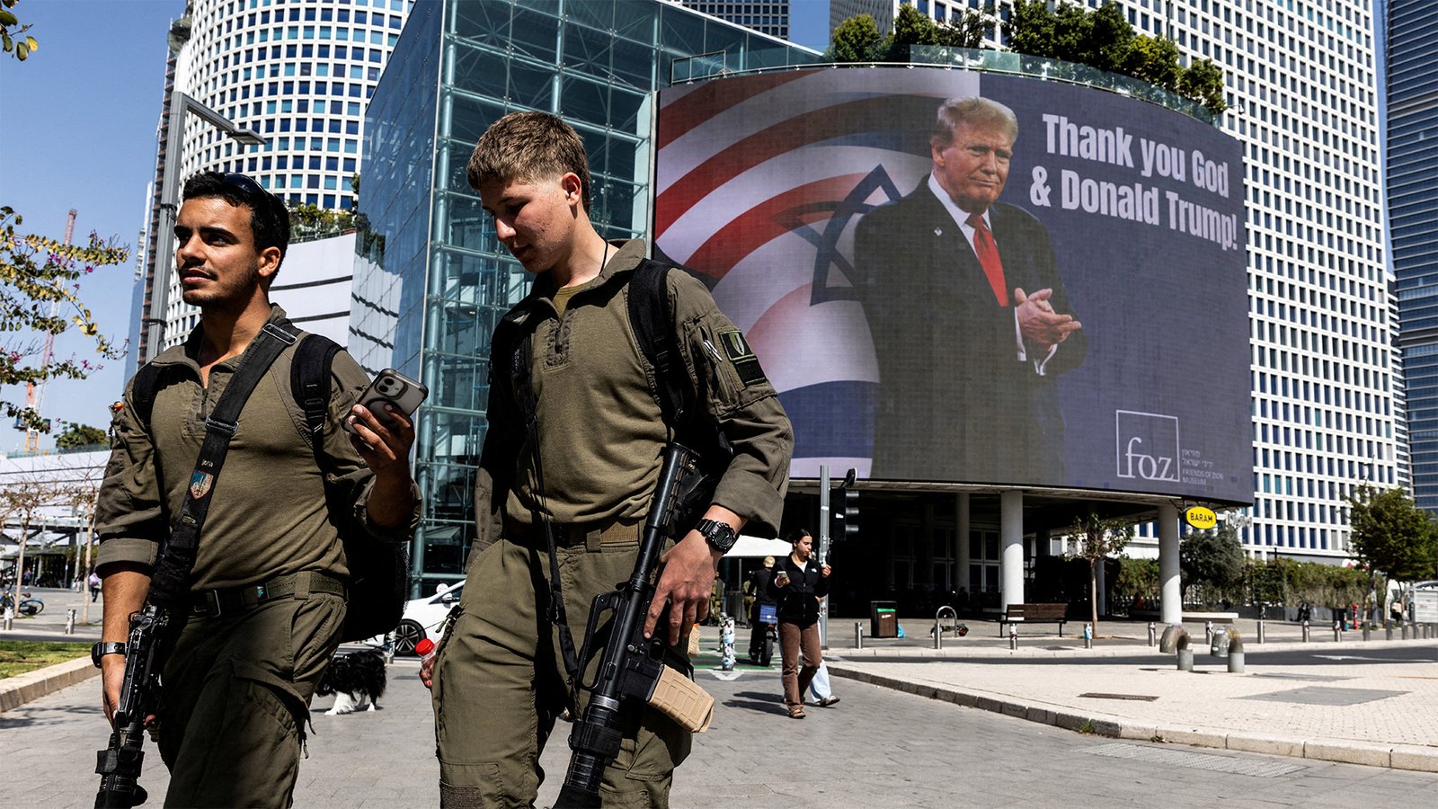 Israeli soldiers walking past a billboard featuring U.S. President Donald Trump with the message 'Thank you God & Donald Trump' in Tel Aviv, Israel