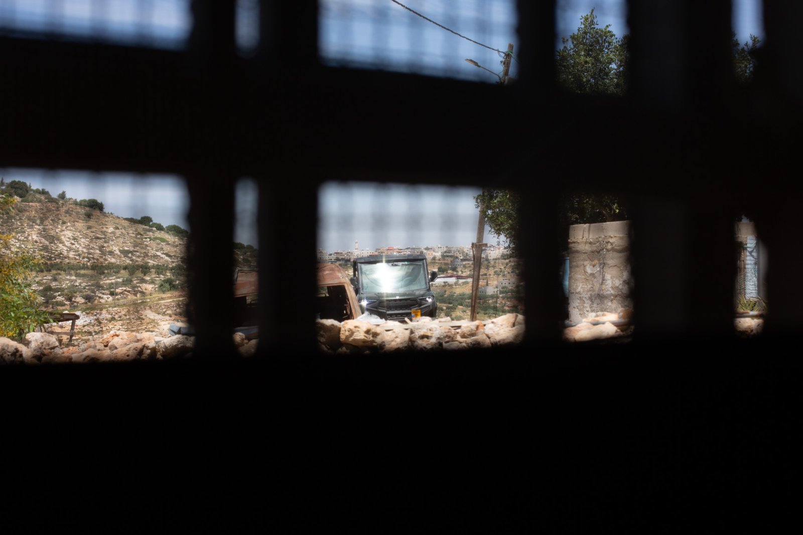 ATV moving across hills beyond compound window