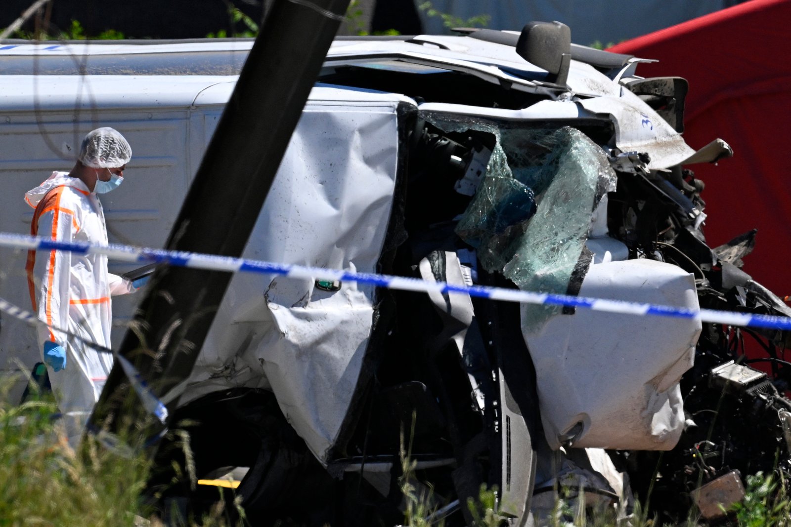 Forensic officer examining wreckage after train hits school bus near Buggenhout