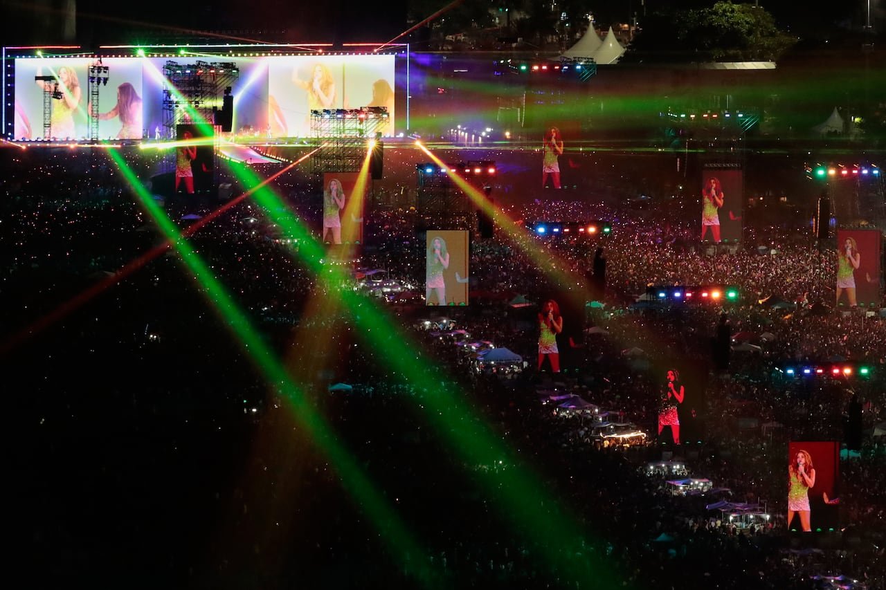 Massive crowd gathered along Copacabana beach watching large screens displaying singer