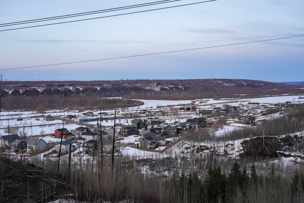 Rebuilt homes nestled within snowy valley landscape viewed atop nearby hill