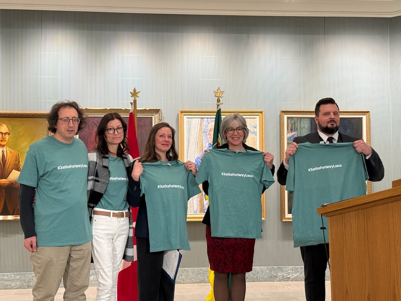 Parents holding #JusticeforHenryLosco shirts alongside officials