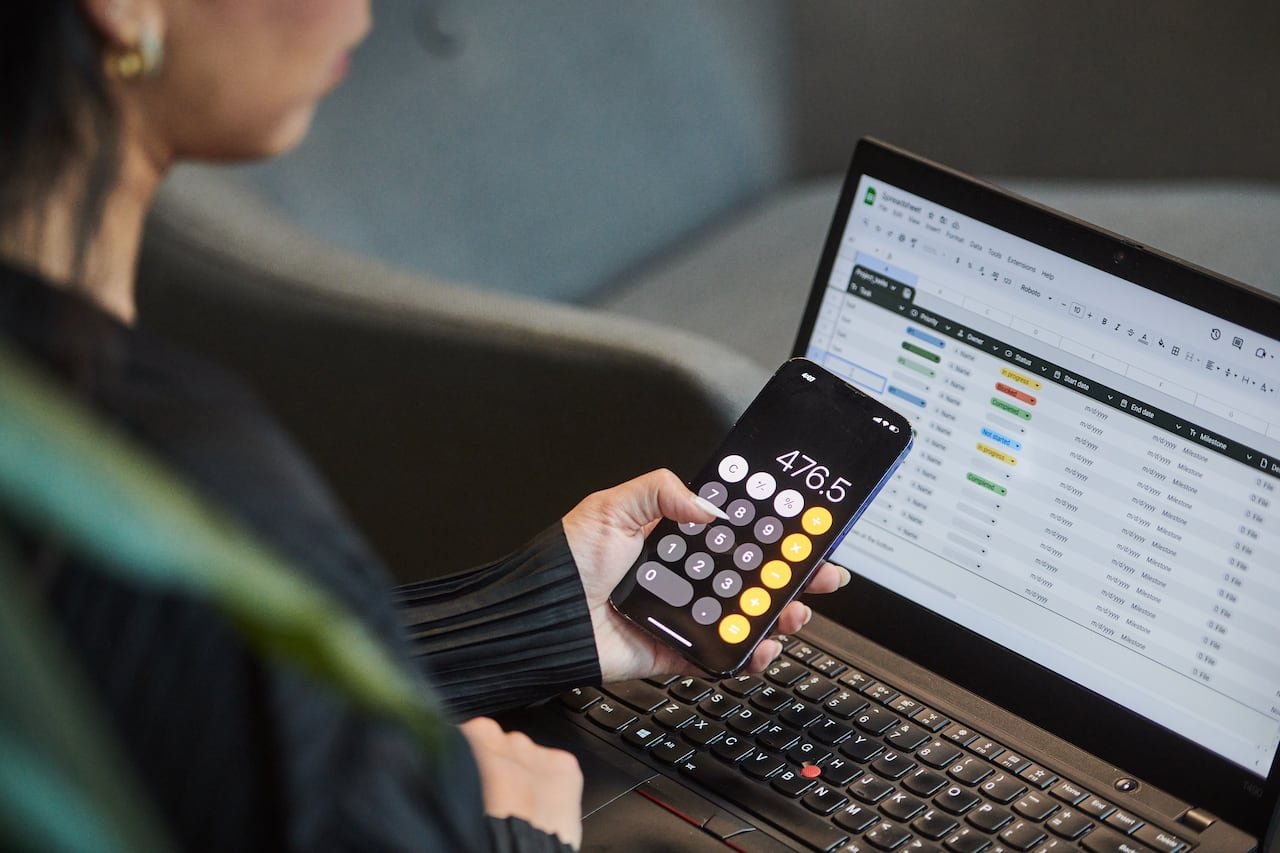 Individual reviewing finances with laptop and smartphone