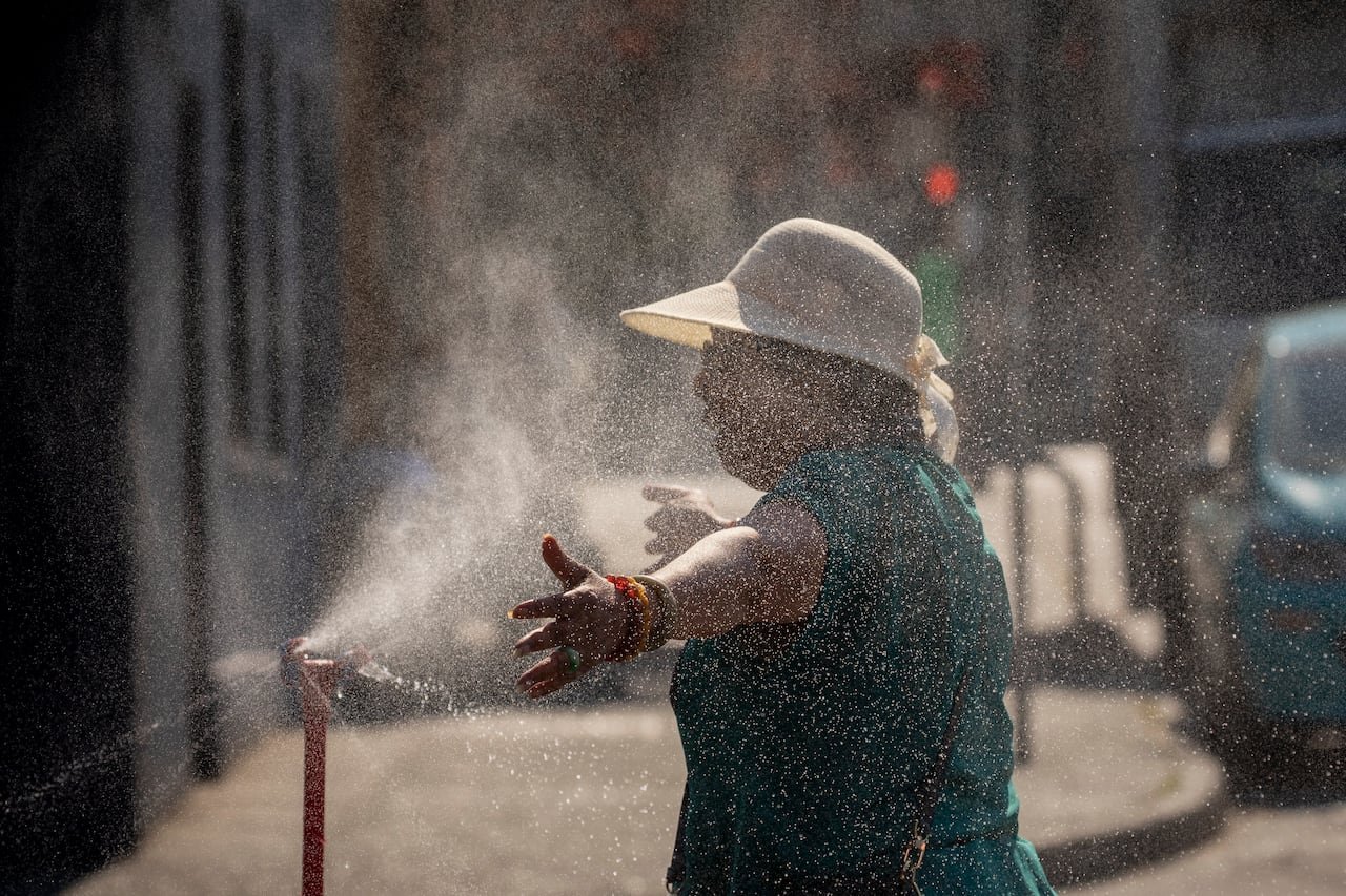 Person cooling off at a community misting station during summer