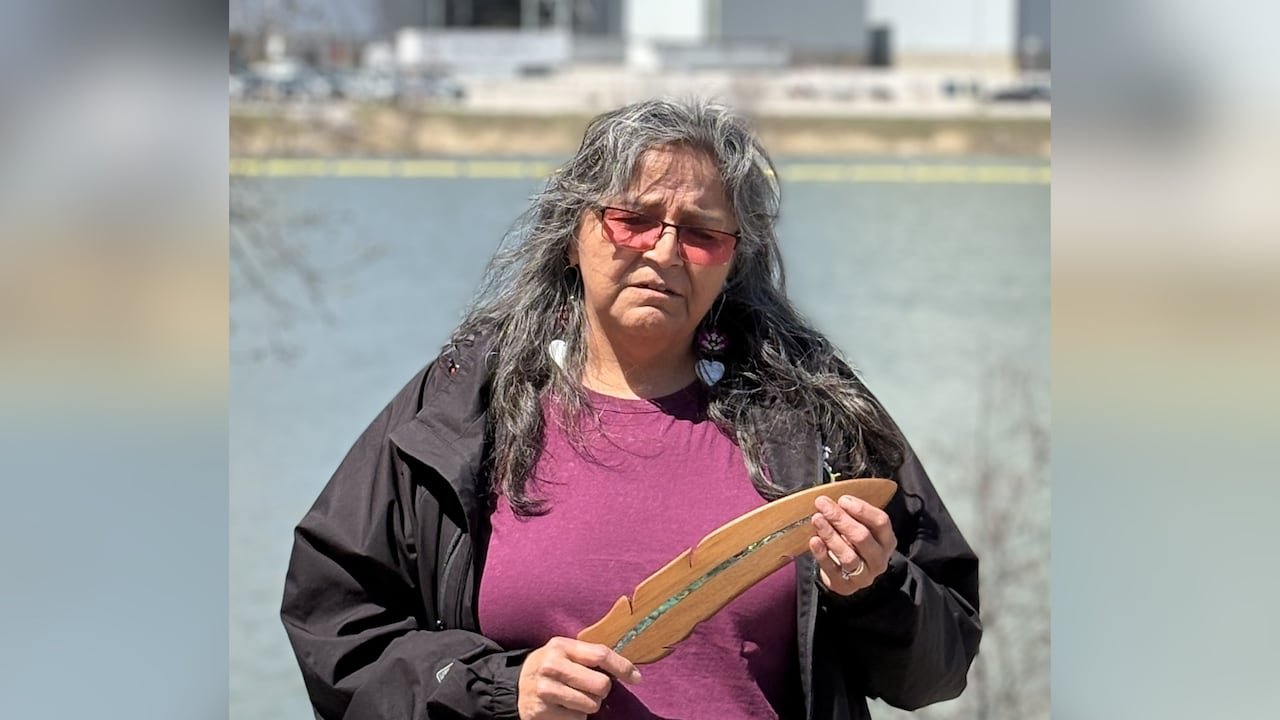 Community member holding wooden feather symbolizing cultural resilience