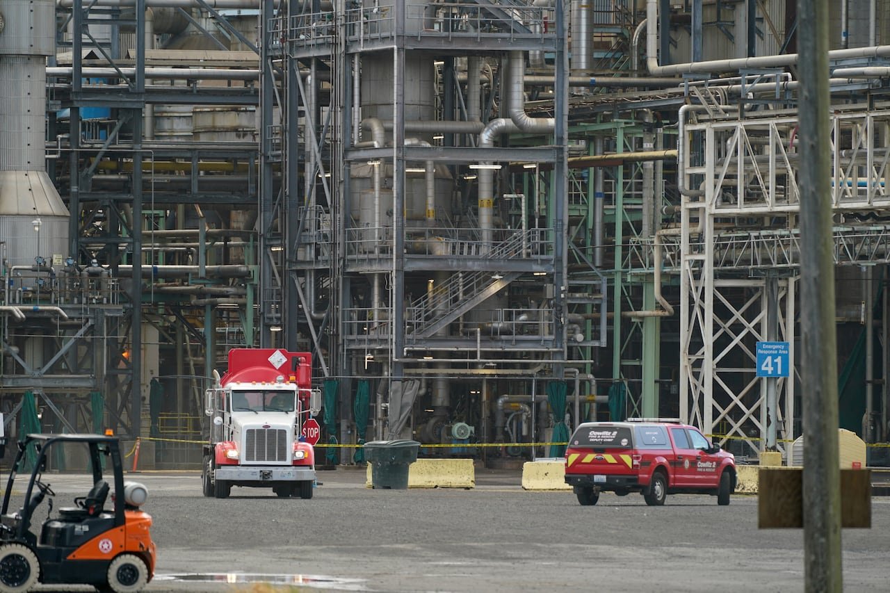 Emergency vehicles drive near factory site.