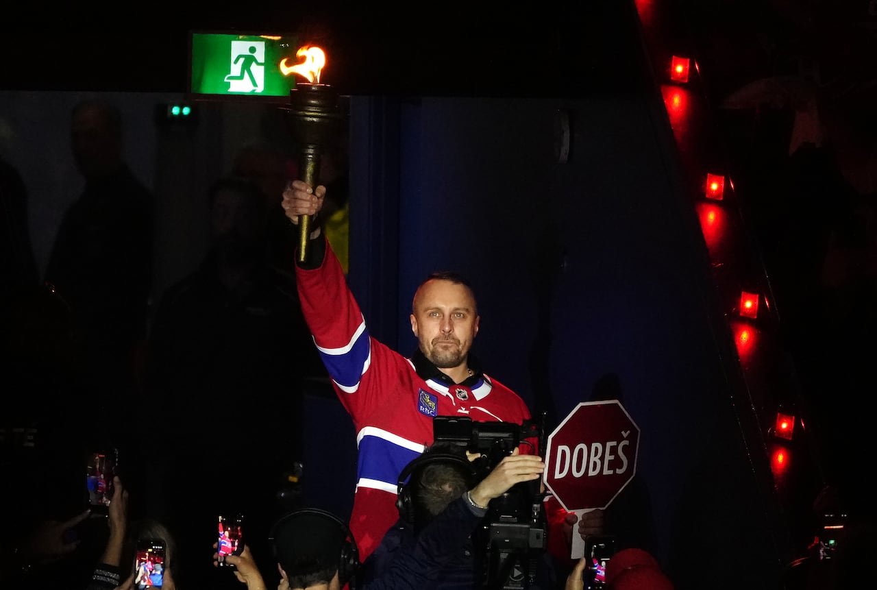 Fan holding torch alongside makeshift stop sign reading 'Dobes'