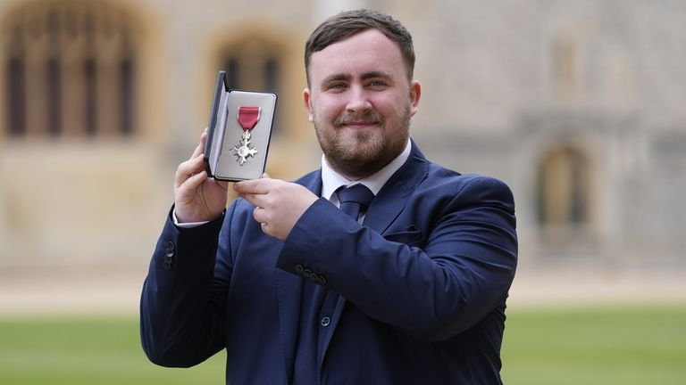 Luke Littler proudly holding his MBE award