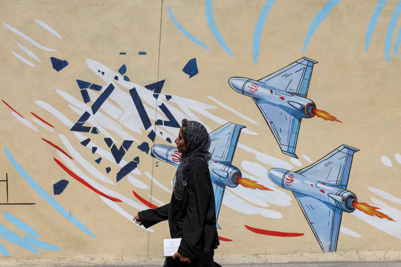 An Iranian woman walks past an anti-Israeli mural in Tehran amid escalating tensions