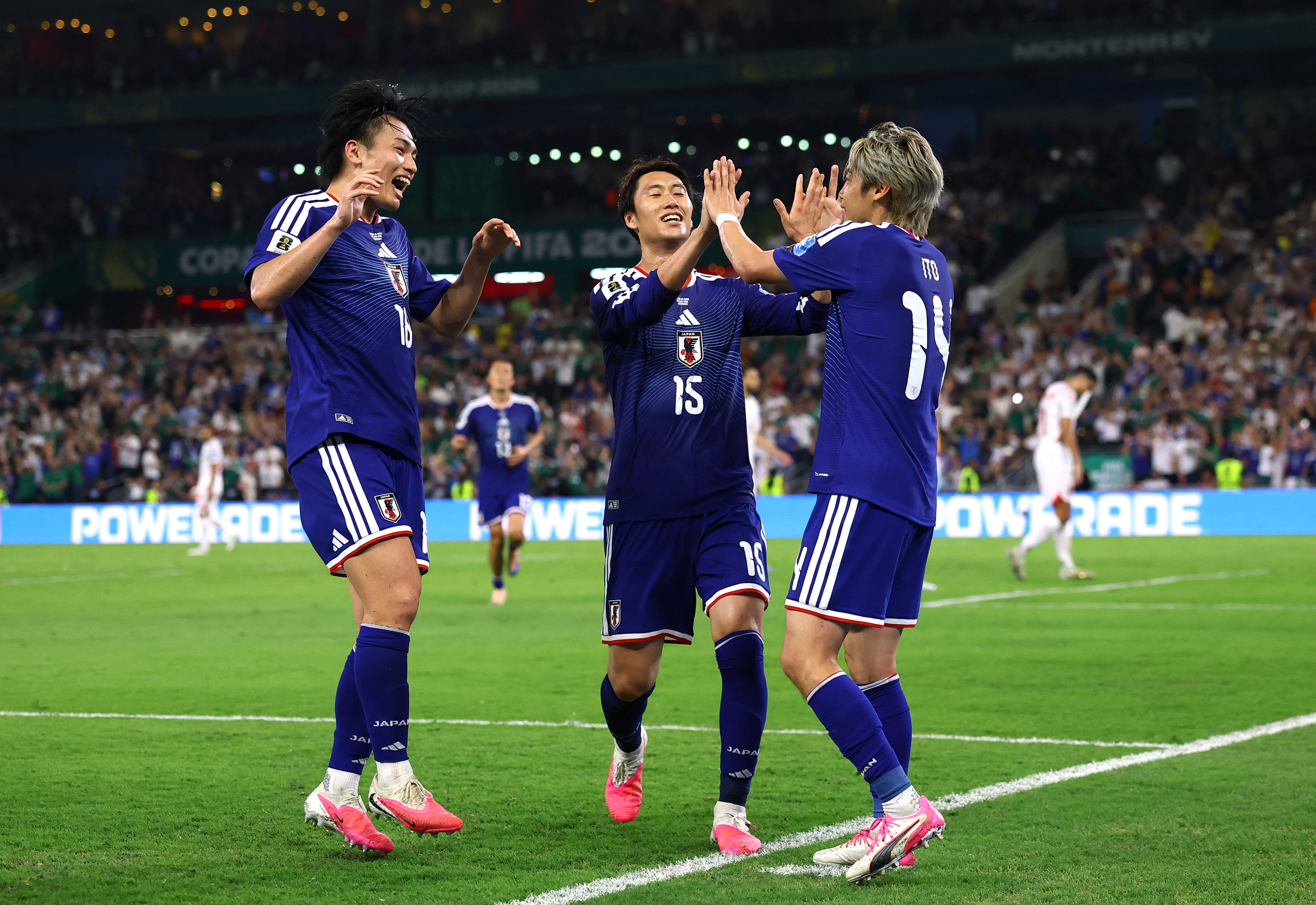 Junya Ito celebrates scoring with teammates Ayase Ueda and Daichi Kamada