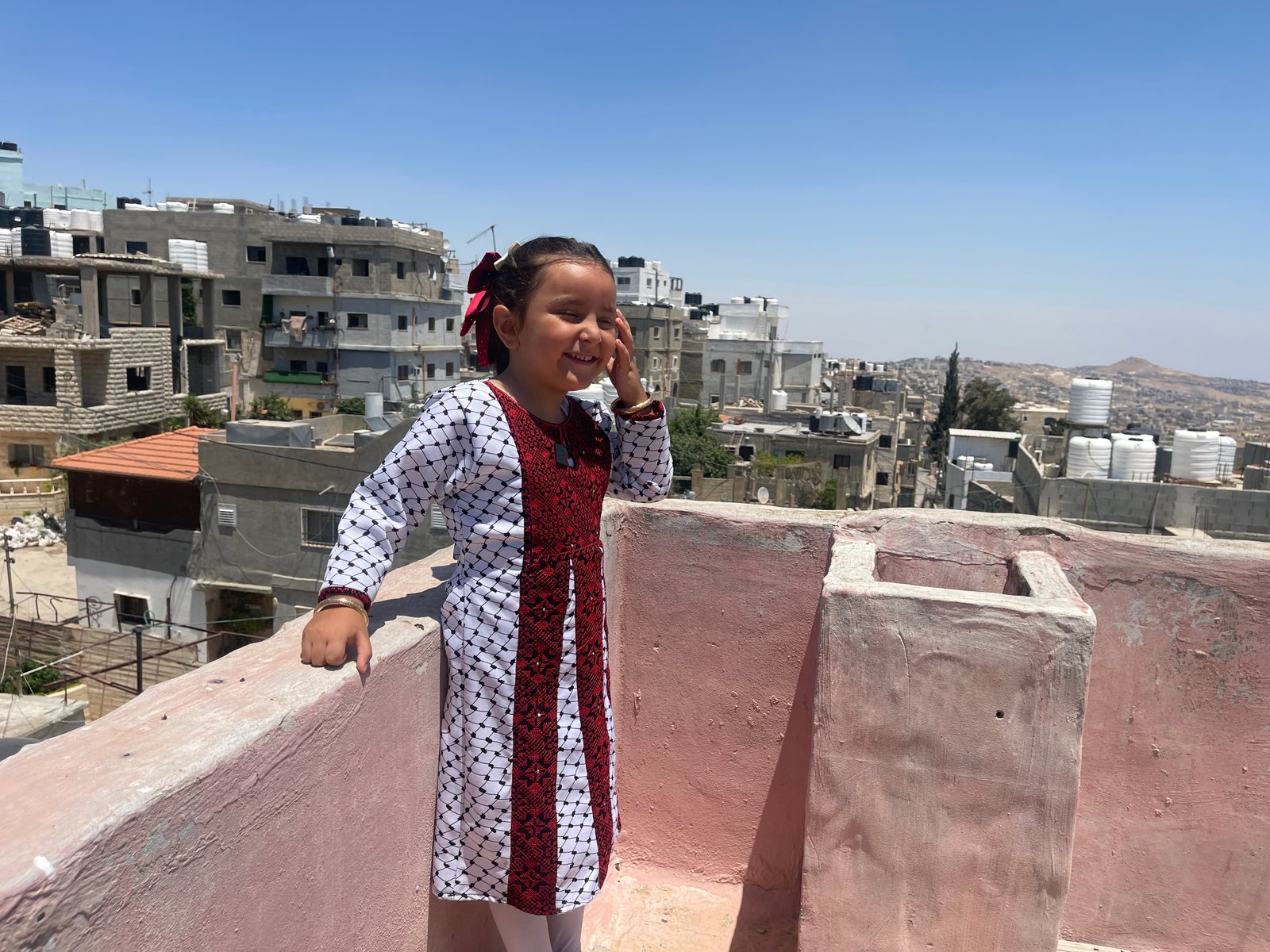 Young girl standing on rooftop overlooking refugee camp
