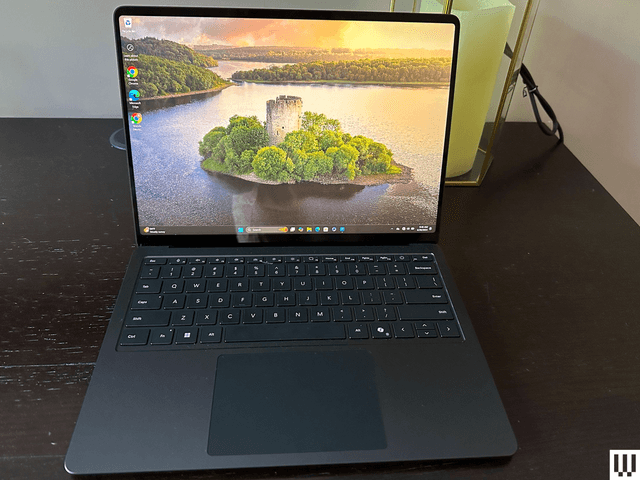 Front view of a laptop sitting on a wooden desk with an island image on screen