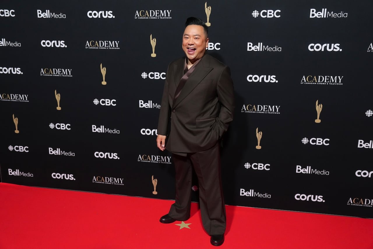 Andrew Phung wearing a sleek dark brown suit on the red carpet.