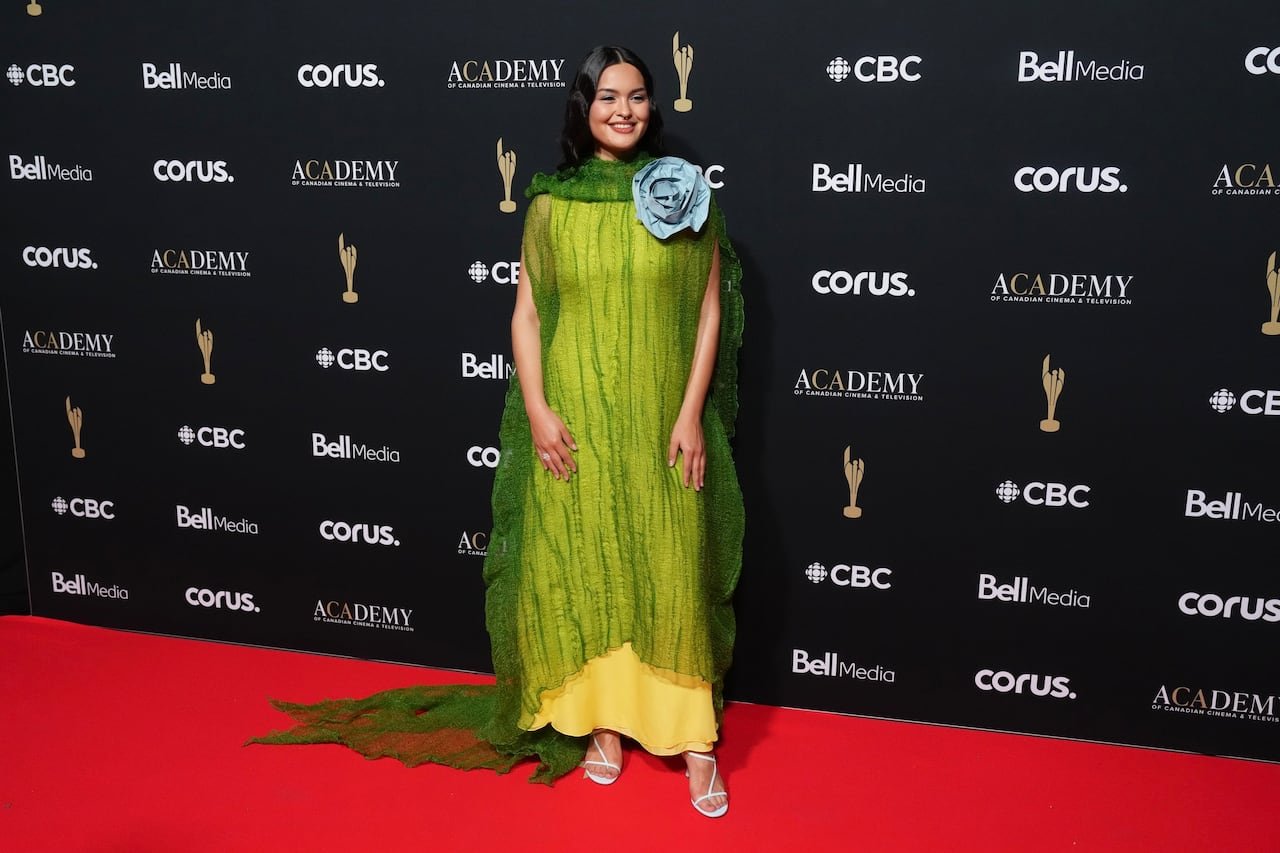 Anna Lambe dressed in yellow vintage dress layered with sheer green fabric adorned by blue floral detail.