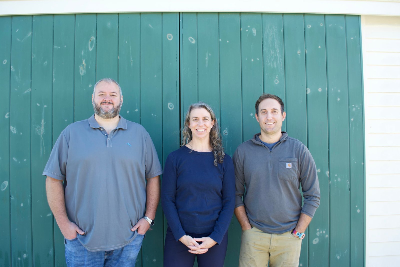 The Dig Energy team stands before a green barn wall.